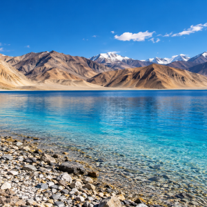 Illustration inspired by Pangong Lake in Ladakh, with turquoise water, a rocky shoreline and barren mountains.